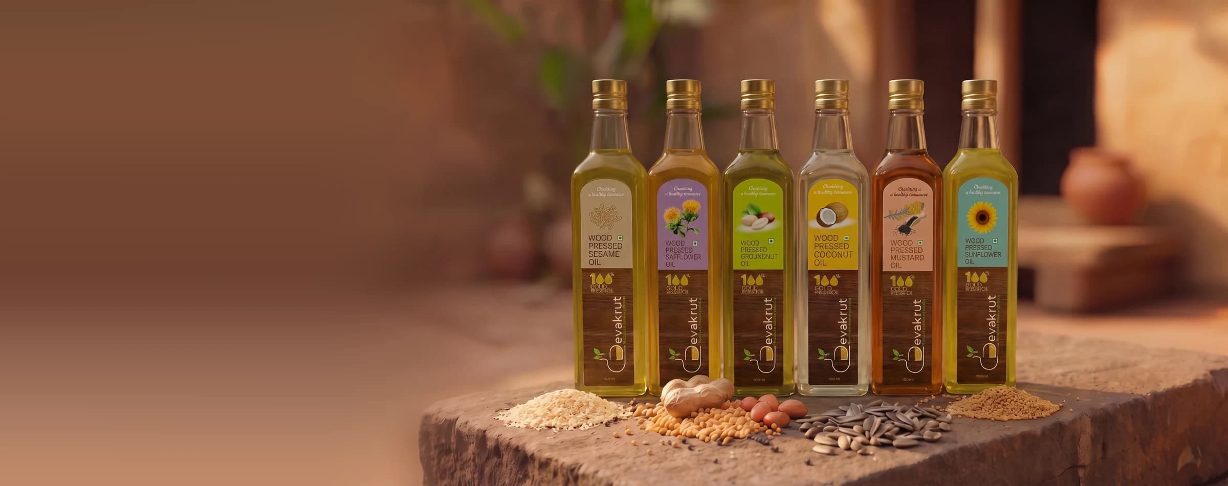 Six Devakrut cooking oils in a row on a stone ledge, with their seeds in front